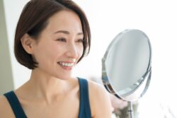ワイヤー矯正で綺麗になった歯並びを鏡で確認する女性