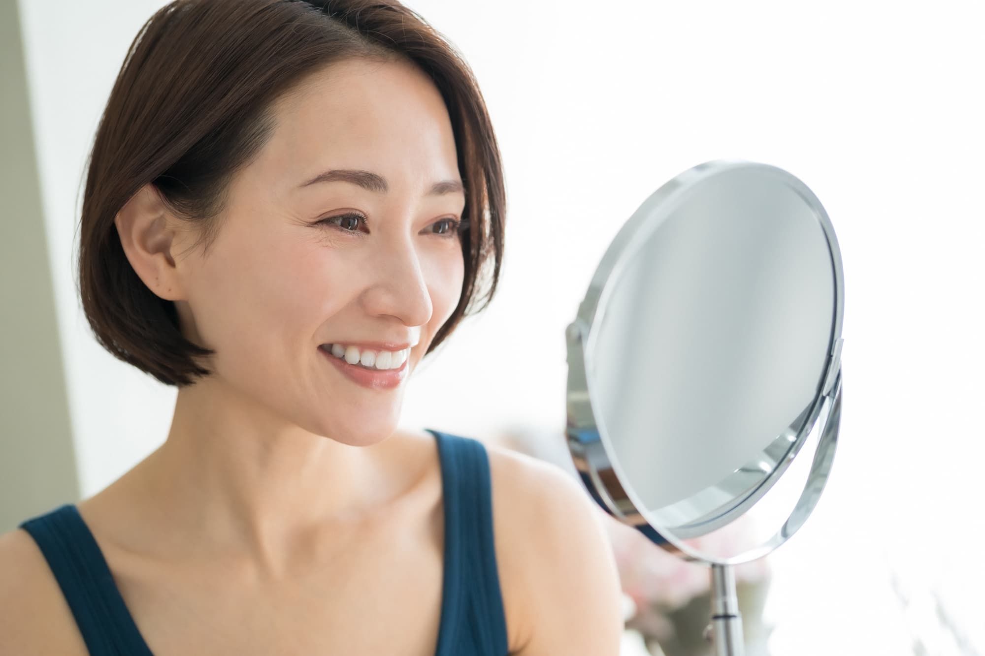 ワイヤー矯正で綺麗になった歯並びを鏡で確認する女性