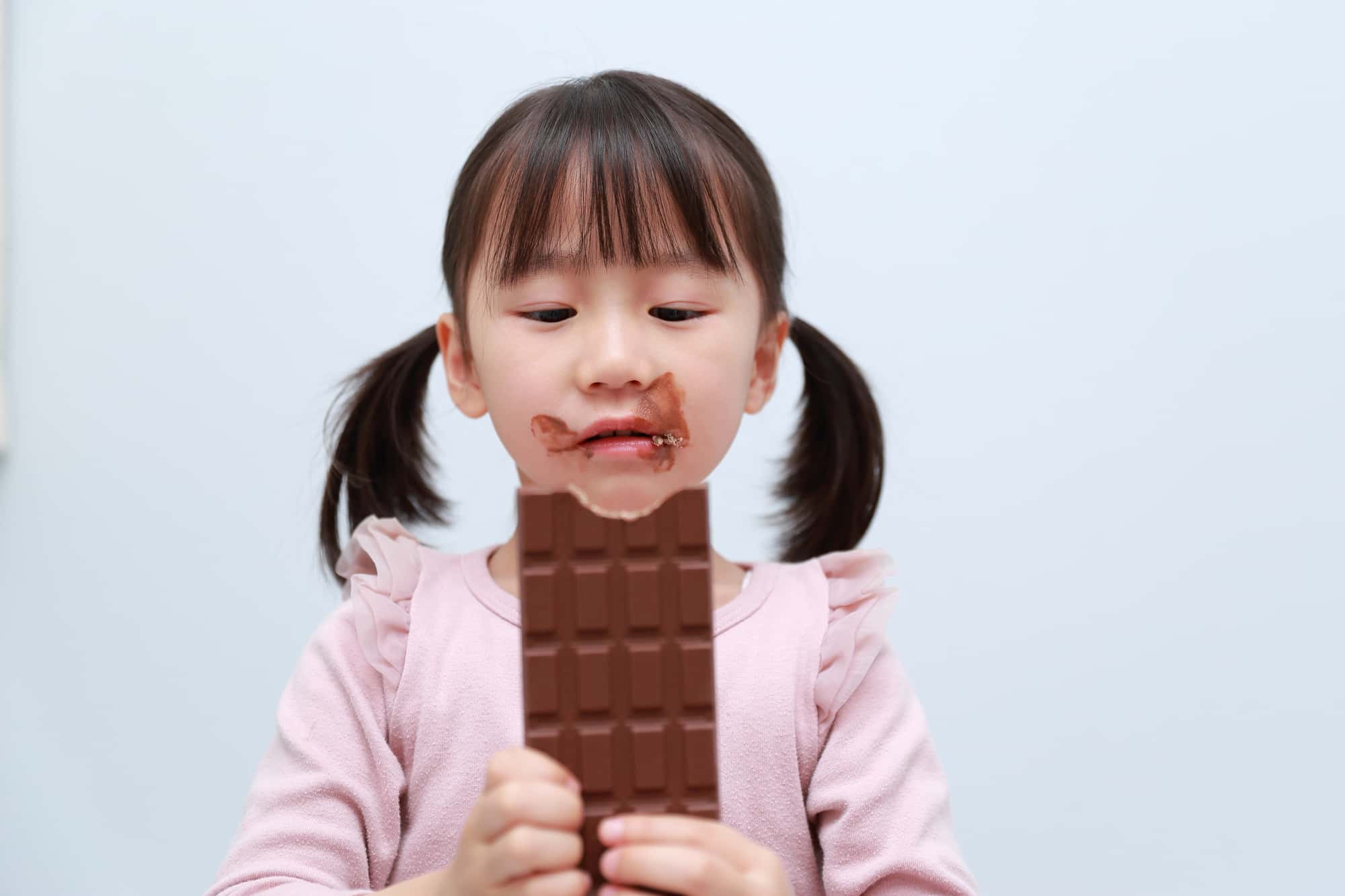 乳歯の虫歯の原因になる甘い食べ物を食べる女の子