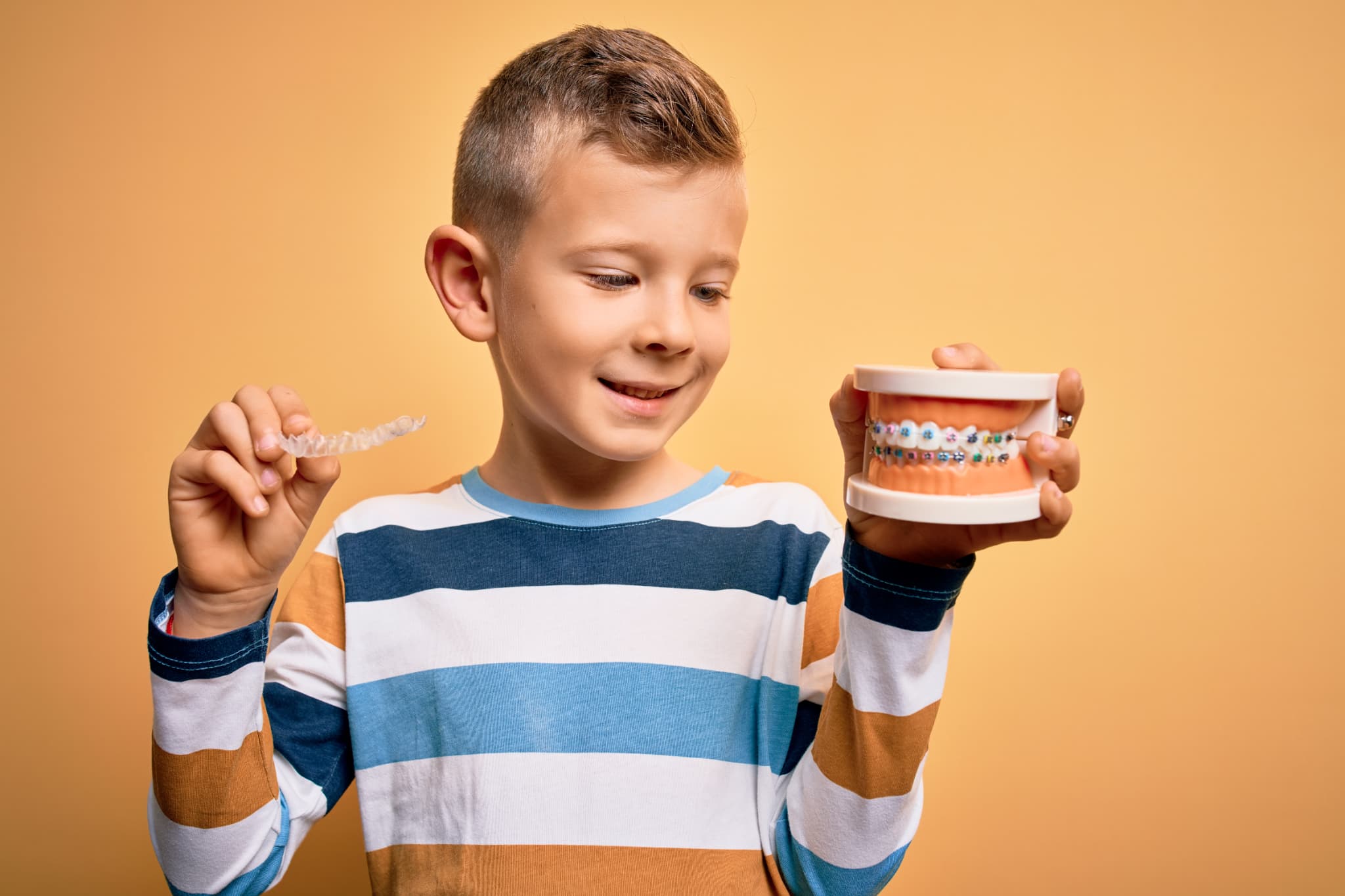 マウスピースとワイヤー矯正の模型を見せる男の子