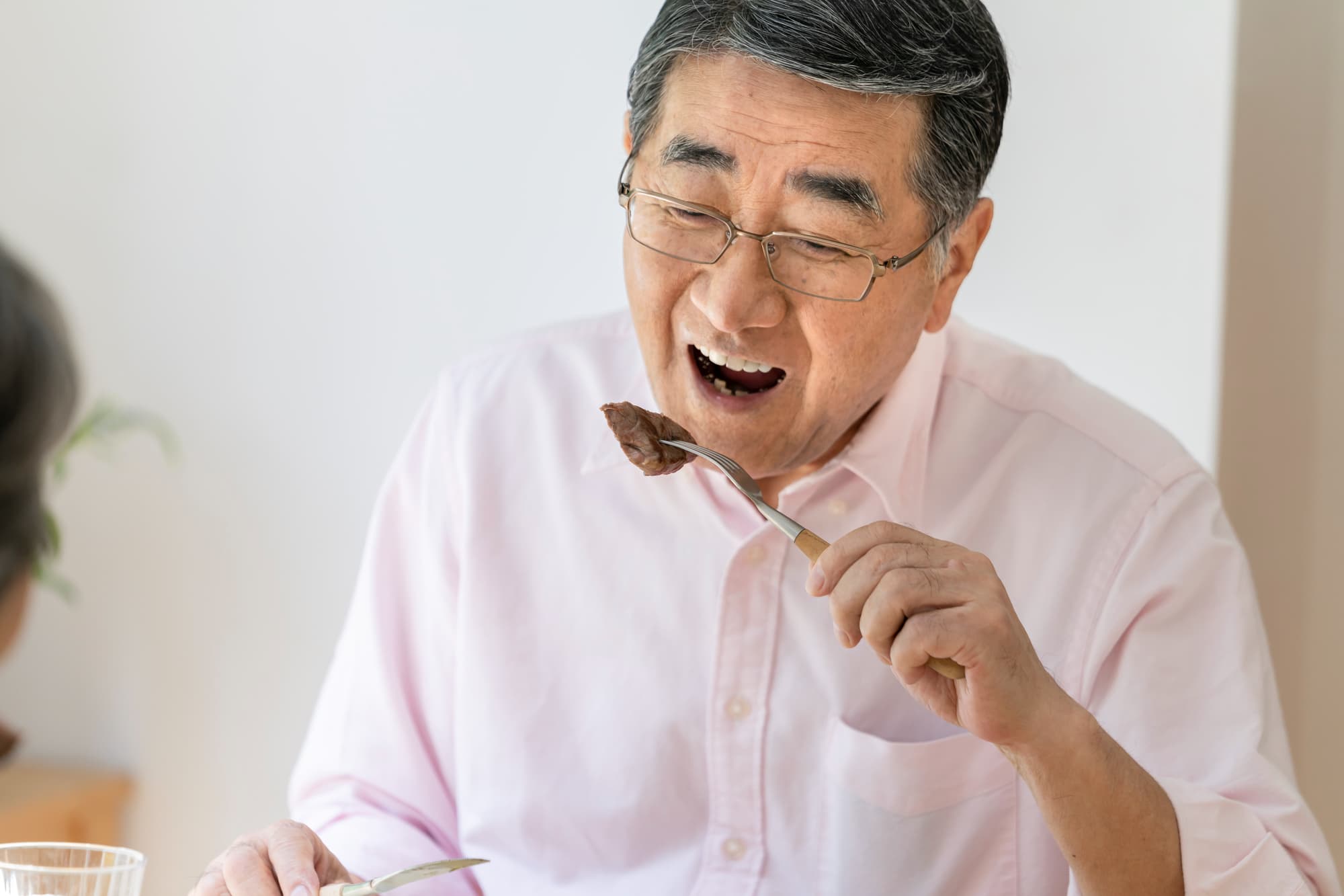 インプラント治療をして食事を楽しむ高齢男性